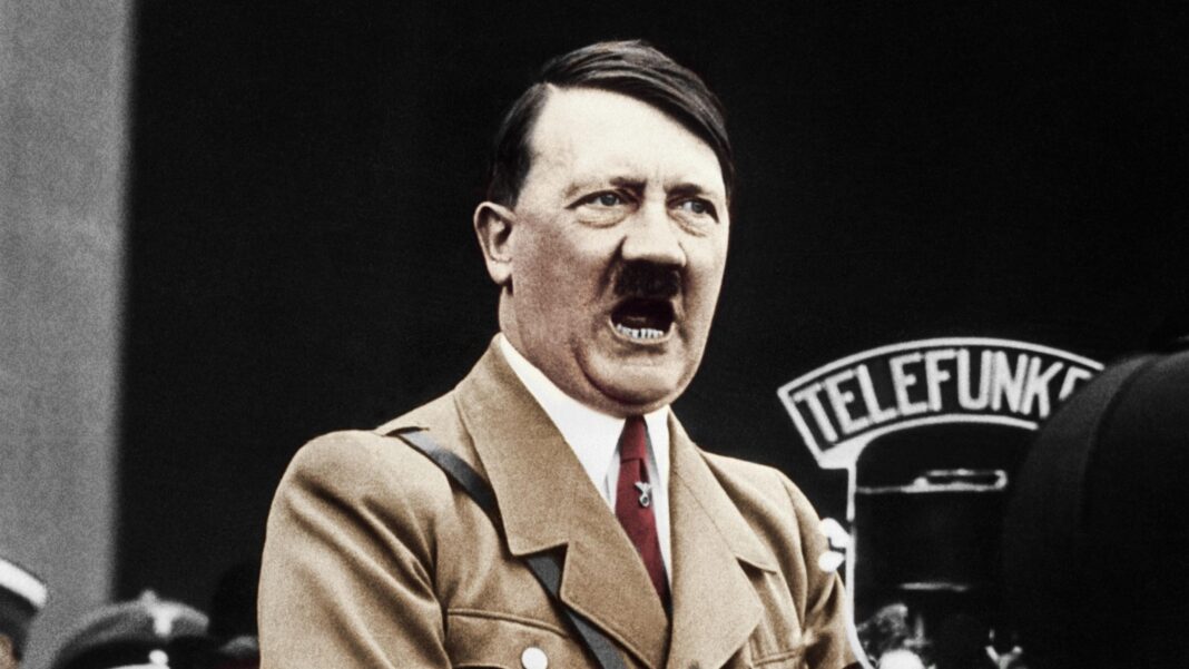 Arrest made after fire at Hitler’s Eagle’s Nest retreat A colour treated photo of Hitler speaking into a big microphone. He's wearing a light brown jacket and red tie.