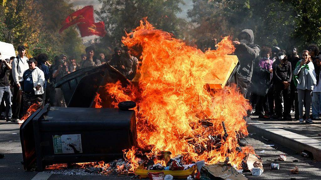 A young man pushes a trash in a fire during an overflow during the blockade of the Lycee Le Corbusier A Aubervilliers, Ile-de-France, France, October 1, 2026