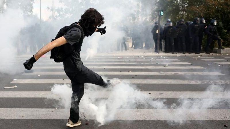 A masked student attempts to kick a tear gas canister amid clashes with French riot police during a demonstration by high school and university students, supported by teachers' union and school parents, in Paris as part of a nationwide day of protests and blockades, voicing anger over overcrowded classrooms, teacher shortages and dilapidated school buildings