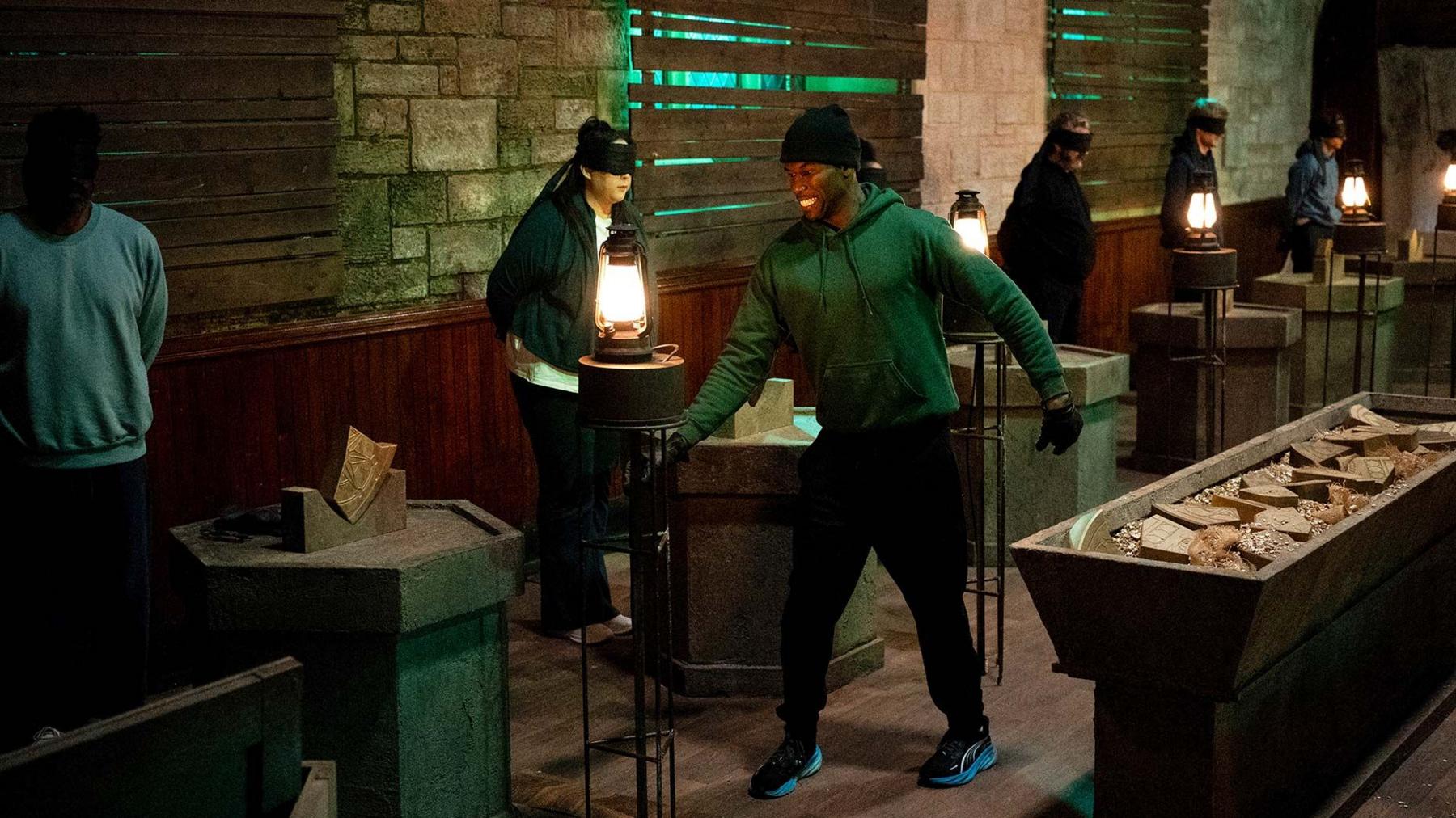 Kenny taking part in the latest celebrity Traitors Mission seen creeping through a dark crypt wearing a green hoodie and black gloves