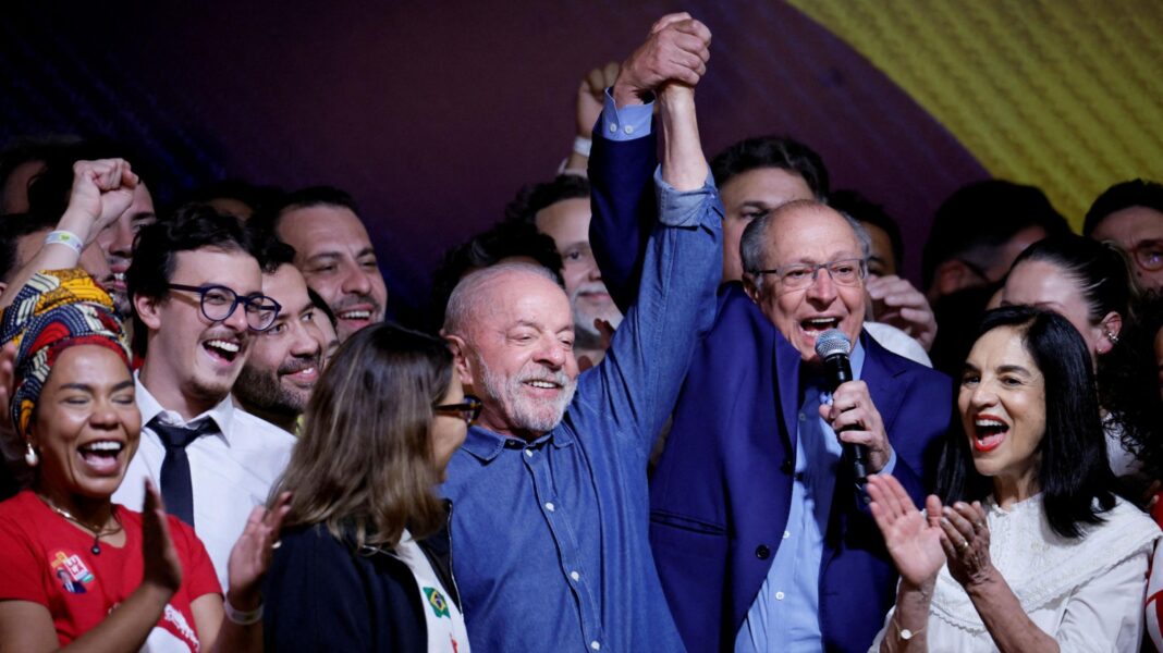 How ‘Lula’s Army’ WhatsApp chat helped turn Brazil election around Lula smiles as his vice-president clasps and holds his hand into the air, speaking into a microphone. A crowd of people are cheering, clapping and smiling around them.