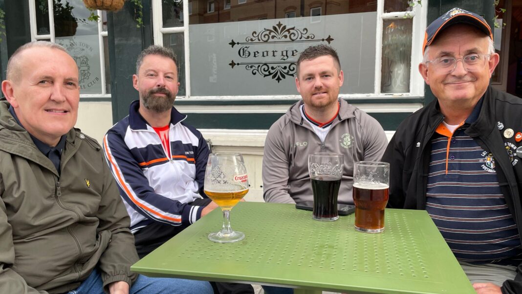 The bitter local rivalry fuelled by a 22-year wait Four Luton fans are sitting around a green table with a mixture of drinks outside a local Luton pub.
