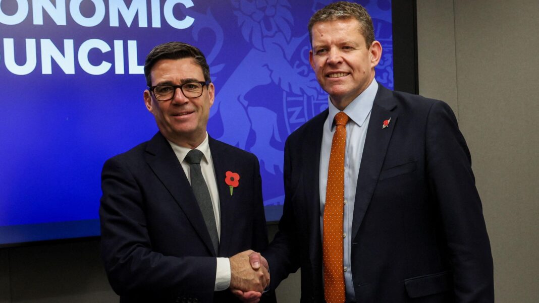 Andy Burnham and Rhun ap Iorwerth shaking hands. Both are wearing black suits and poppies.