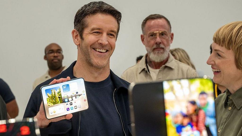 Apple boss John Ternus showing off the new iPhone Duo to visitors at the firm's headquarters.