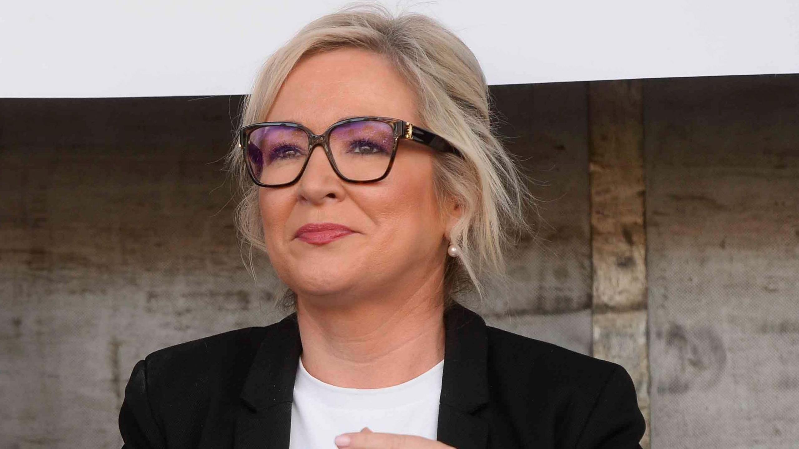 Michelle O'Neill, with blonde hair, tied back. She is wearing a white top and black jacket.