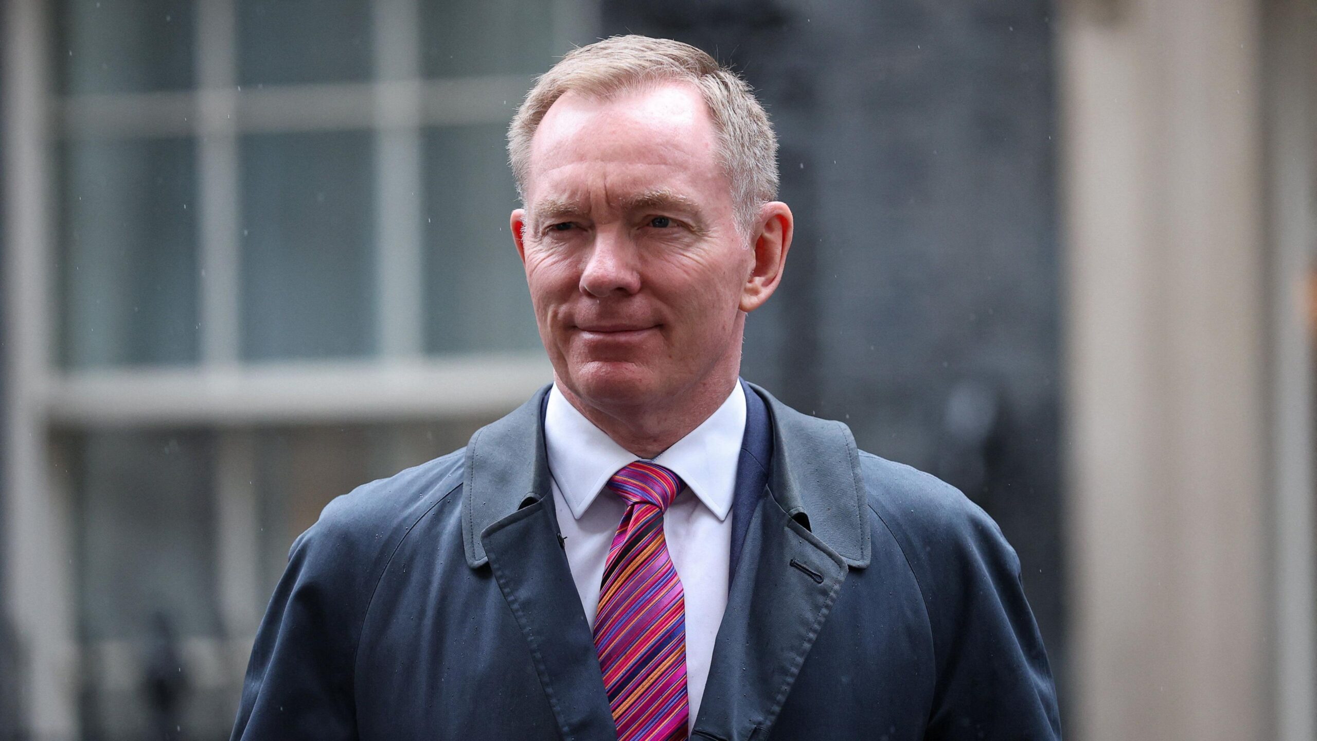 Northern Ireland Secretary Chris Bryant - a man with short, greying fair hair, smiles as he walks on Downing Street in London.  He is wearing a pale shirt, a pink tie with multicoloured diagonal stripes and a navy overcoat.  The photo was take in early September.