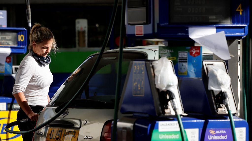 A blonde woman fills her car up with diesel