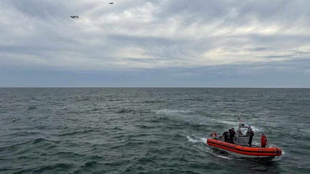 All six passengers presumed dead after plane went missing off US coast A bright red coast guard vessel at sea with crew onboard, and two aircraft in the distant sky overhead