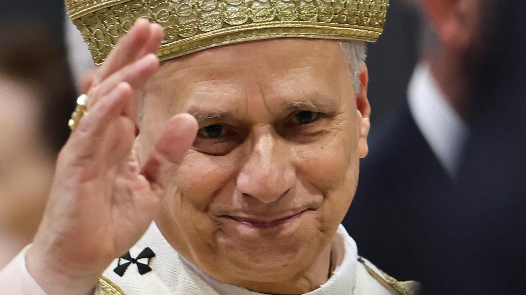Close-up of Pope Leo's face with raised hand, as he leaves after a Mass on Sunday 2 May