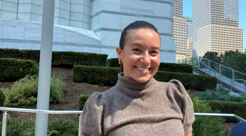 Emily, a young woman with brown hair tied back, smiling at the camera
