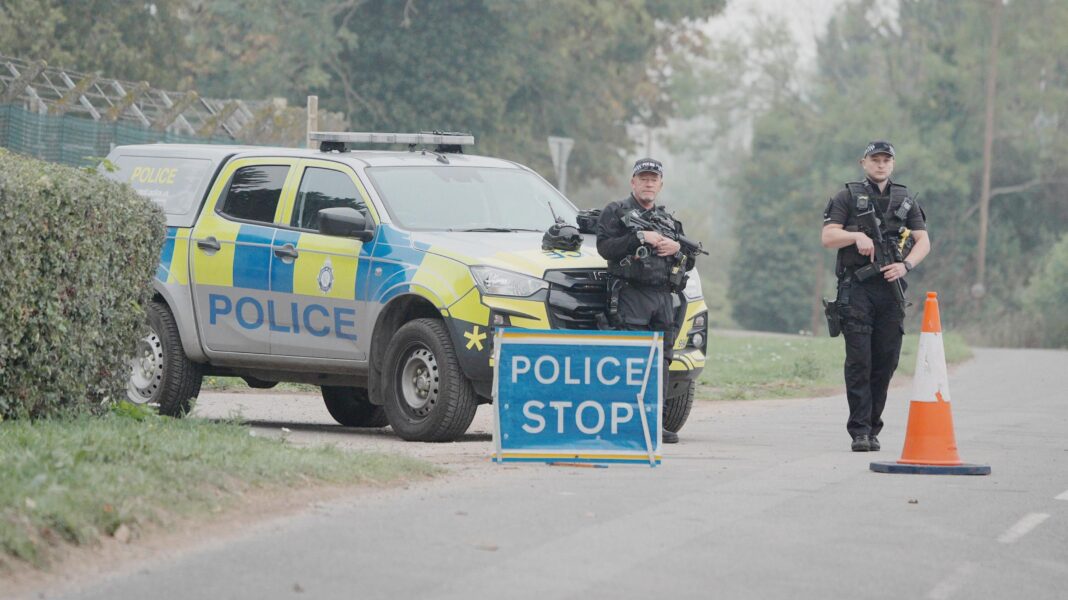 Britain won’t tolerate threats on our soil, Miliband says as he summons Iran ambassador Police stand near a stop sign and a police vehicle near RAF Fairford