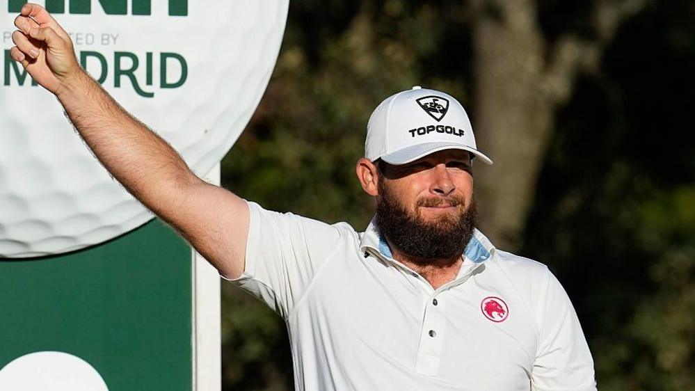 Tyrrell Hatton holds his arm out on the golf course