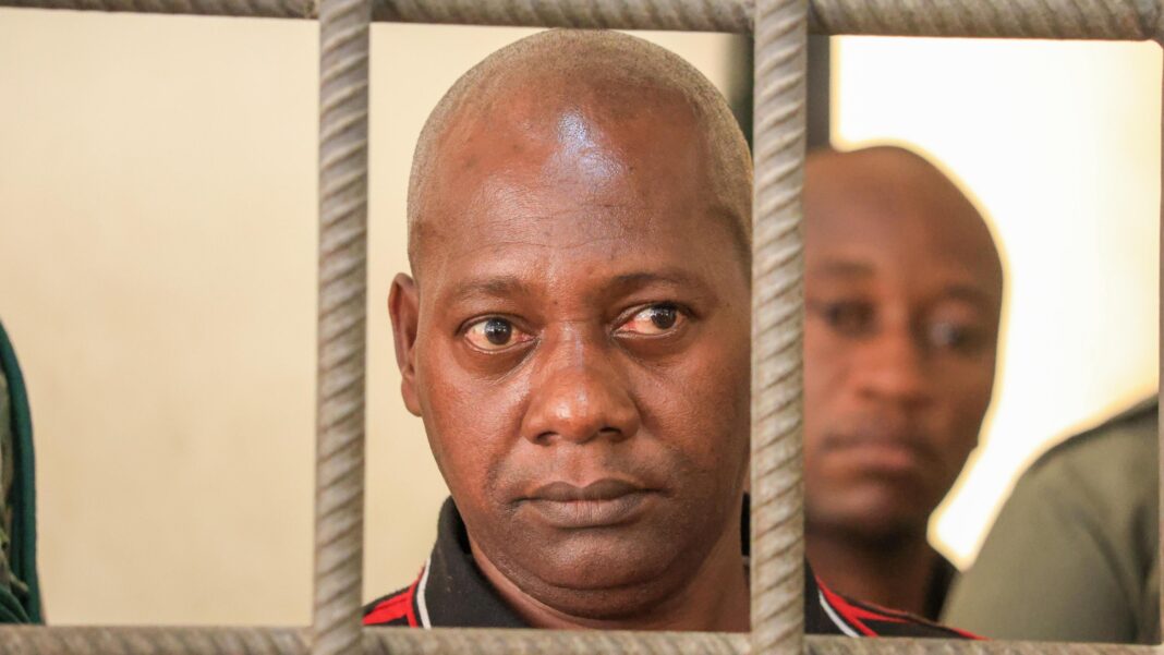 Kenya pastor accused of ordering parents to starve children to death faces verdict A close shot of a bald man looking through the bars of a cell