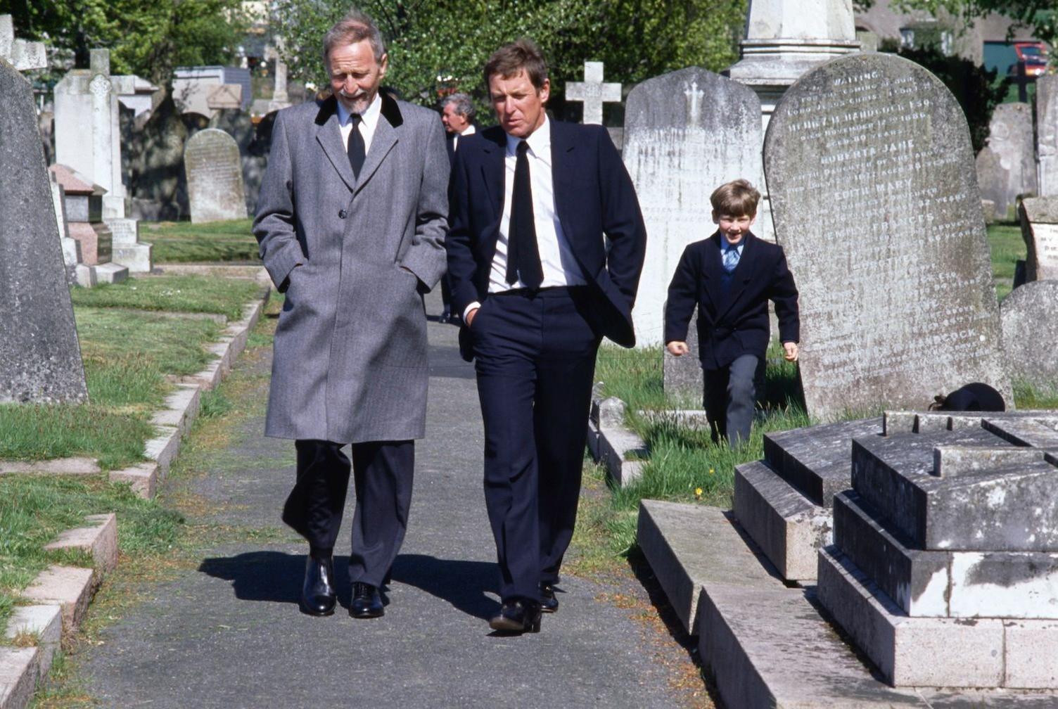 A still image showing John Nettles on the set of Bergerac in a graveyard