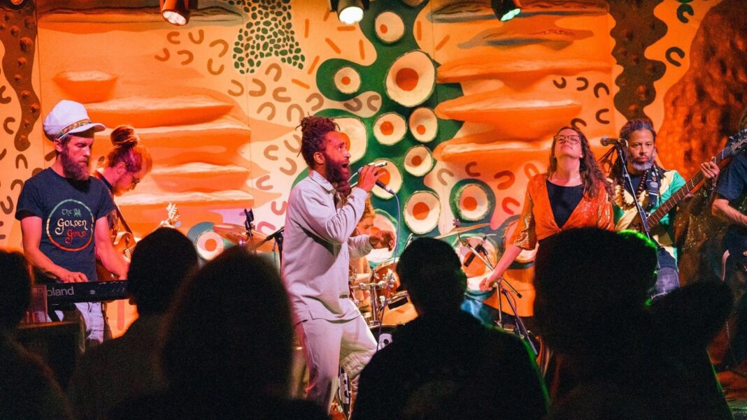 A band performing on stage in front of a colourful abstract painting at the Jam Jar in Bristol.