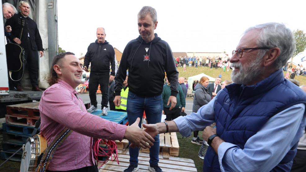 A man in pink shirt about to shake hands former Sinn Fein leader Gerry Adams, a man with grey hair and beard, near the Garvaghy Road in Portadown.