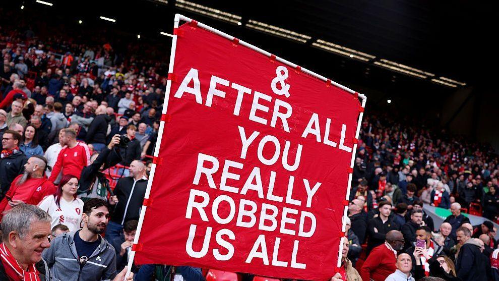 Liverpool fans holding a banner which reads "And After All You Really Robbed Us All'.