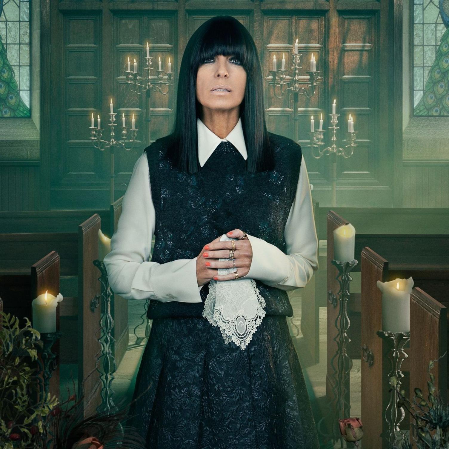 Claudia Winkleman in a white shirt, black sleeveless jumper and long black skirt; she's holding a white lace handkerchief