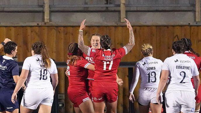 Three Canada players, in red kits, celebrate