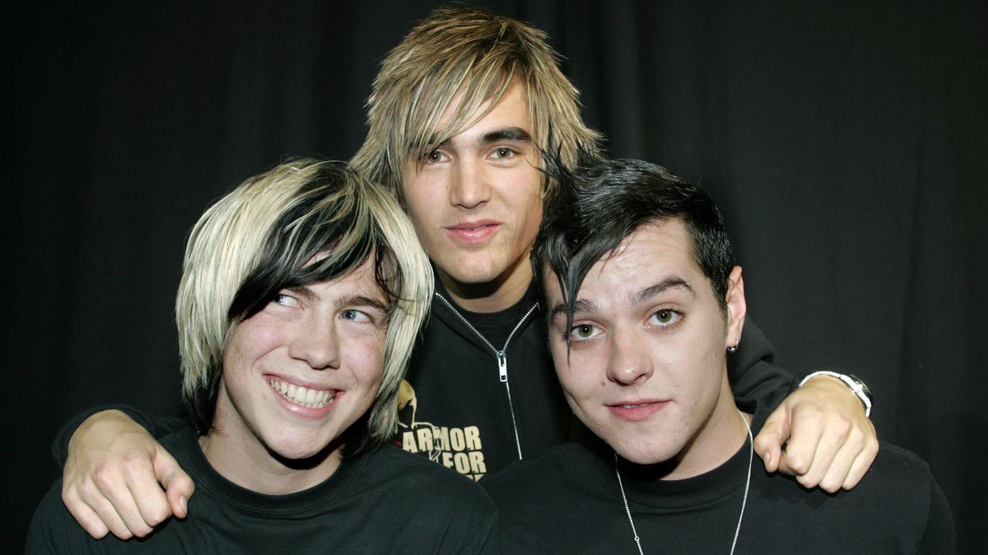 Bourne standing and posing with Charlie Simpson and Matt Willis in 2004; Simpson has his arms around the other two's shoulders