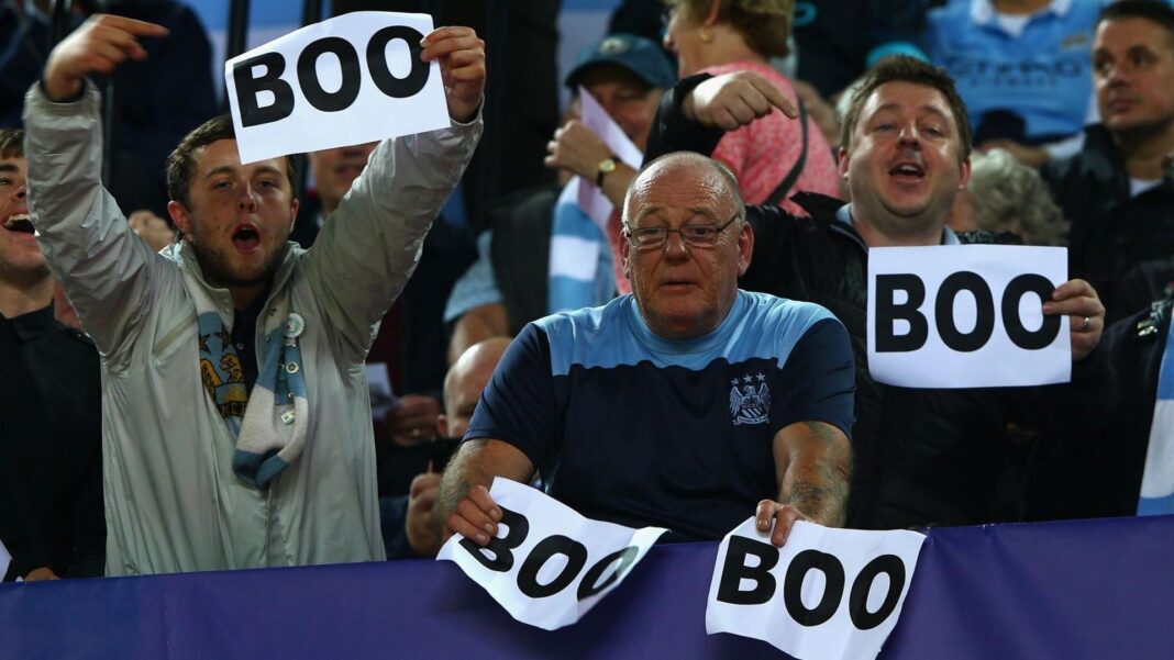 Why do Man City fans boo pre-match anthems? Manchester City fans holding signs reading 'BOO'