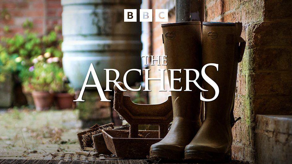 A pair of brown Wellington boots are visible next to a brick wall. The image is emblazoned with the words "The Archers".