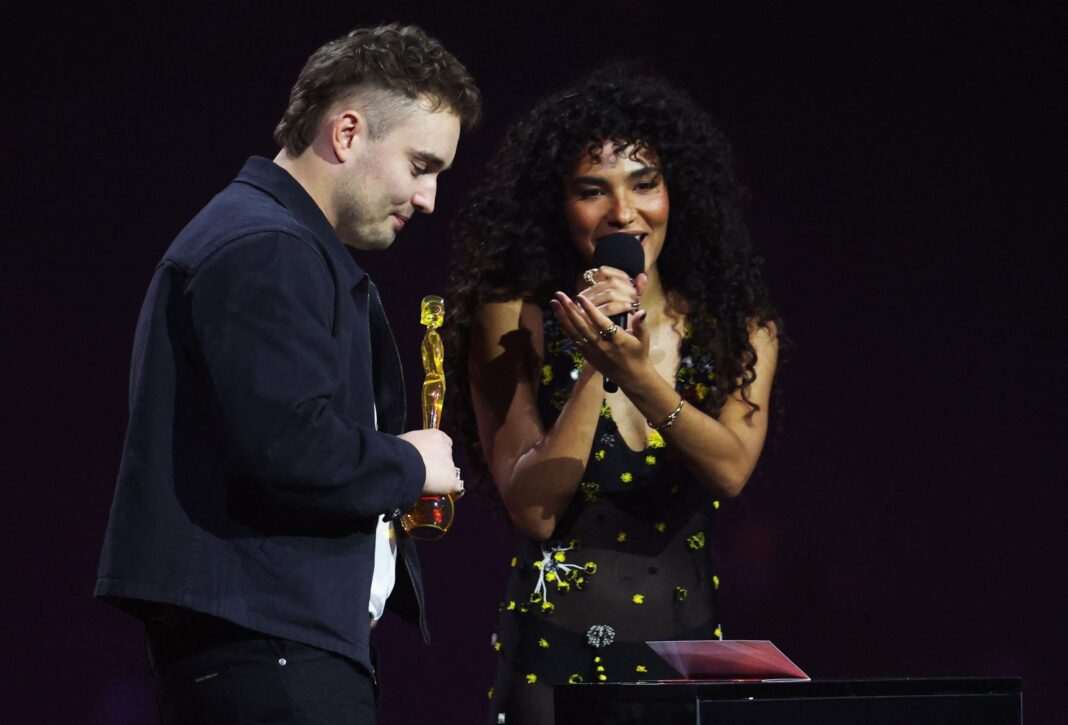 Olivia Dean speaks on stage next to Sam Fender, during the BRIT Awards at the Co-op Live Arena, in Manchester, Britain, February 28, 2026.