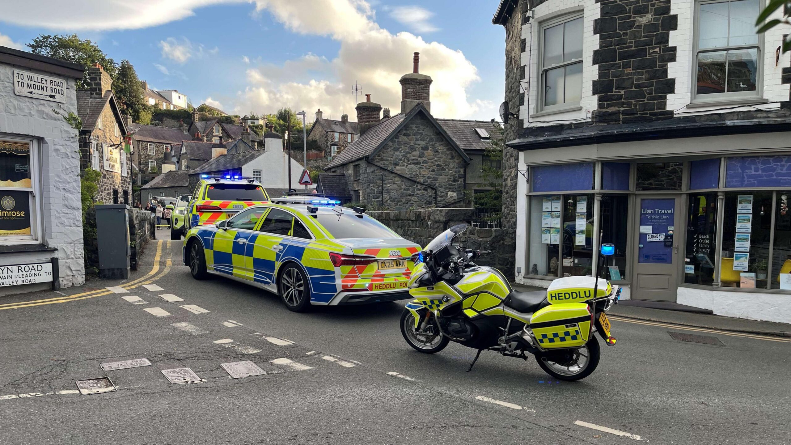 Police vehicles on a high-street road in a town