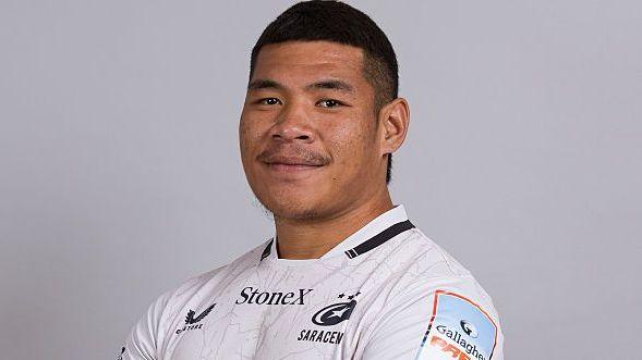 Totoa Auvaa standing for a team issue photo, wearing white Saracens kit looking towards the camera