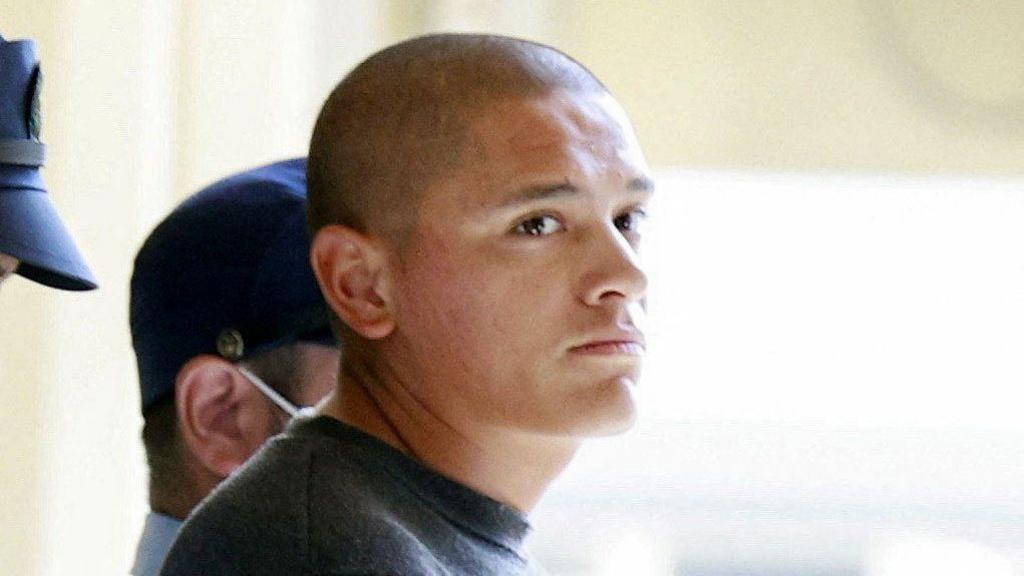 Devin Jacob Ballard, who has a shaved head and blue jumper, leaves a police station to be sent to prosecutors over the killing of a Japanese woman.