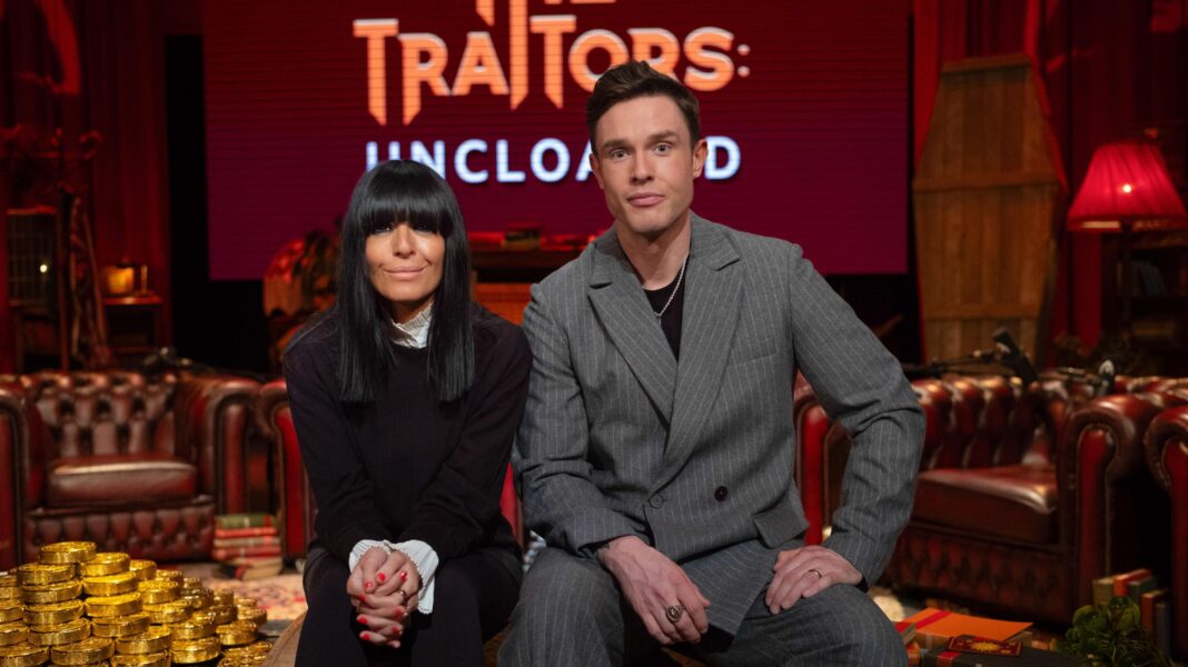 Claudia Winkleman wears all black as she sits next to Traitors: Uncloaked podcast host Ed Gamble, who wears a grey suit.