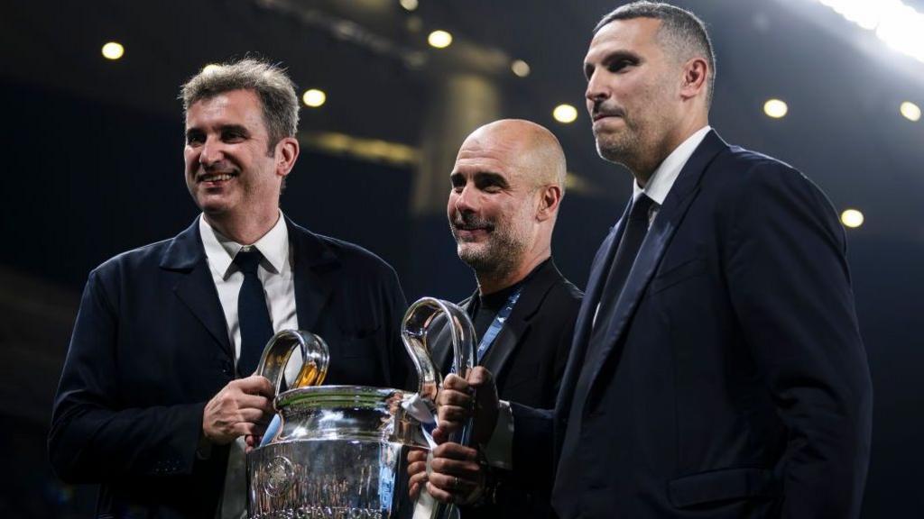 Manchester City CEO Ferran Soriano, manager Pep Guardiola, and chairman Khaldoon Al Mubarak smile while holding the Champions League trophy after the club beat Inter Milan 1-0 in the 2023 final at the Ataturk Stadium in Istanbul, Turkey