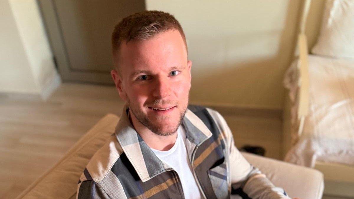 Wearing a a checked jacket and with short hair, Tim Wulf looks up at the camera.