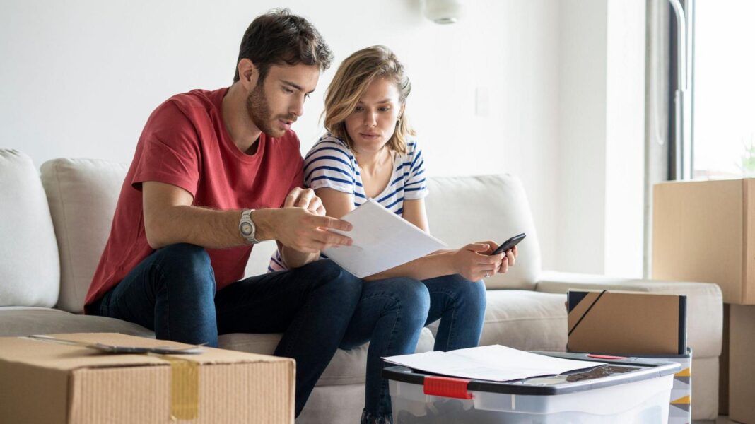 Banks say Healey is planning Budget tax raid on their profits Young couple sat in a living room surrounded by cardboard boxes