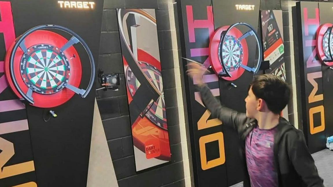 Welsh teenager Makinley Cooper-Johnson, from Wrexham, pictured throwing at a dartboard.