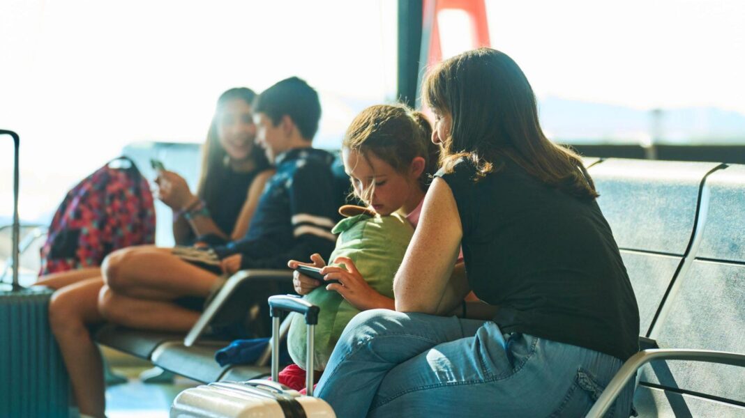 Girl and woman sitting an airport departure gate