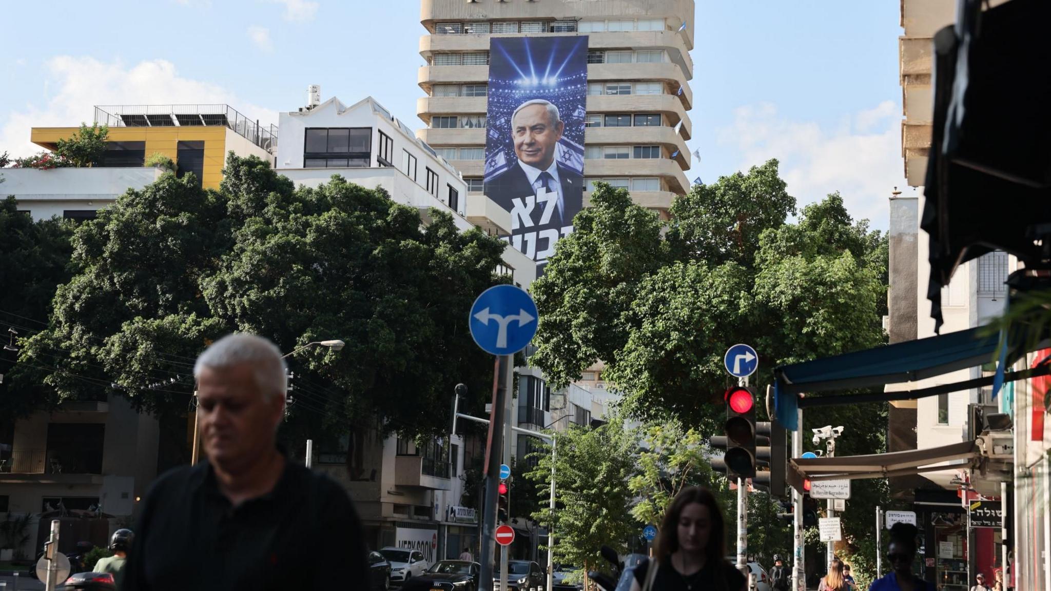 A large banner hung from a tower block in Tel Aviv, Israel, shows Israeli Prime Minister Benjamin Netanyahu with the Hebrew phrase, "We will not surrender" (6 October 2026)