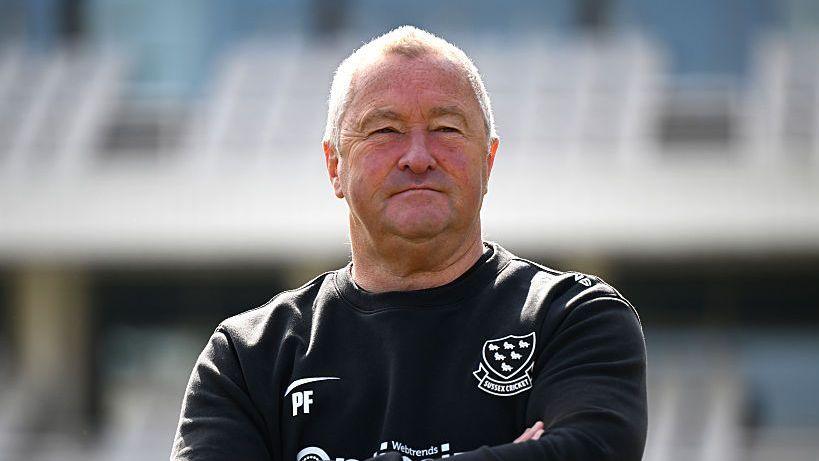 Paul Farbrace stood with a black Sussex sweatshirt on with initials PF on the right corner