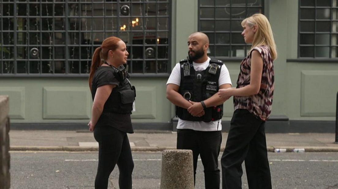 PC Zoe Ticehurst and Detective Constable Faisal El Issaoui talk to BBC correspondent Sonja Jessup. They are all standing on a pavement outside a pub at the spot where a fatal shooting took place.