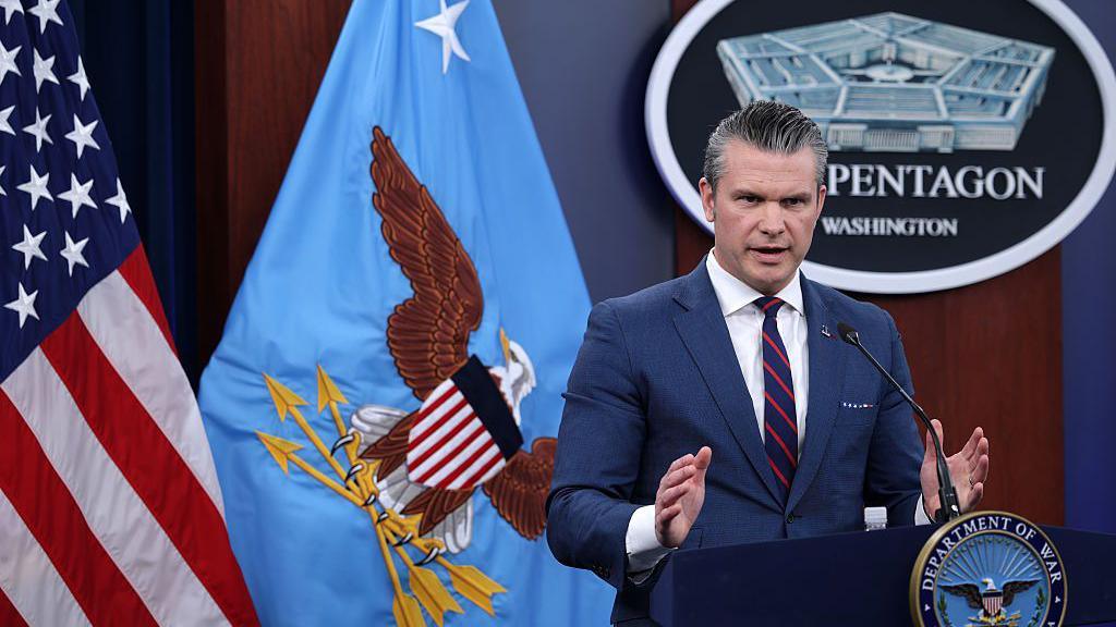 Secretary Hegseth in front of US flags at The Pentagon