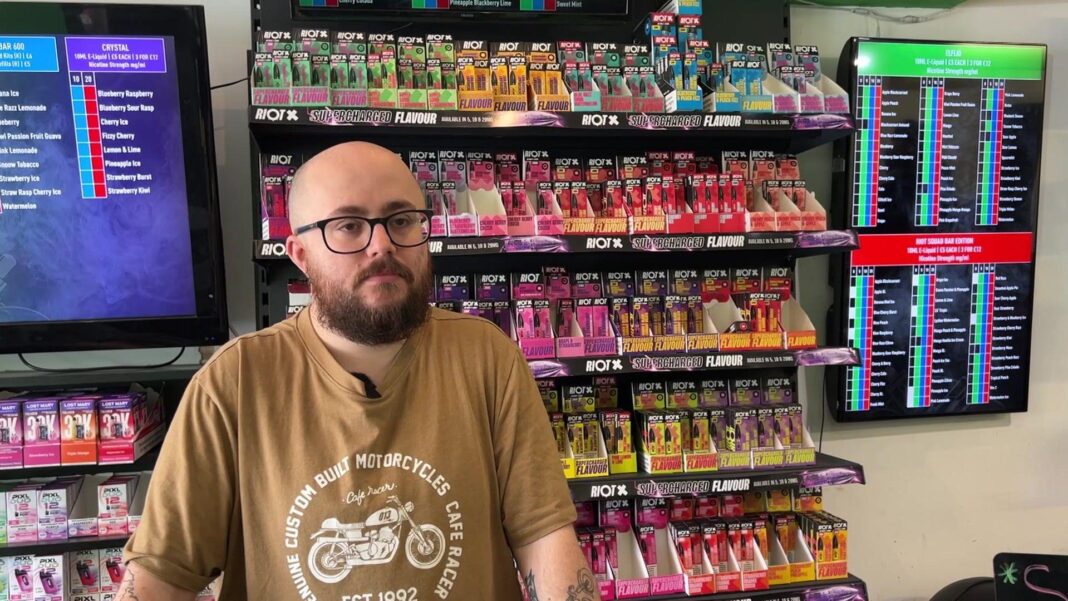 Vape prices to rise as new tax takes effect Jordan standing at a counter in a vape shop