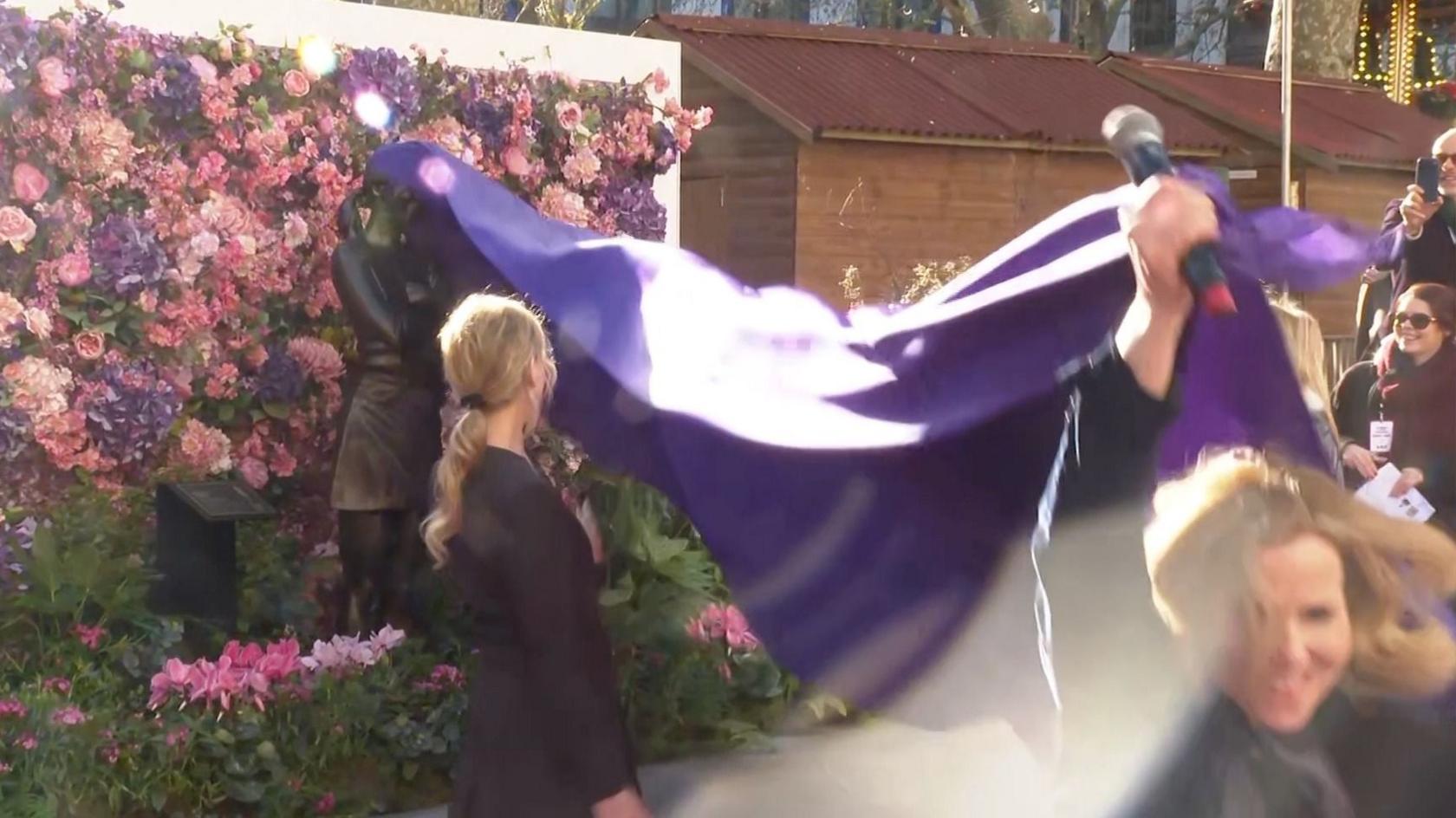 Actress Sally Phillips pulling purple rug and unveiling Bridget Jones statue