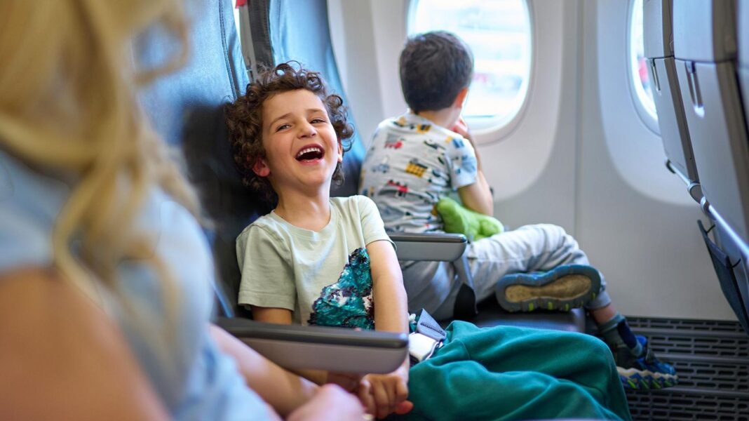 Move to stop charges for parents to sit by children on flights A child laughs while sitting on a plane next to a younger sibling on one side and parent on the other