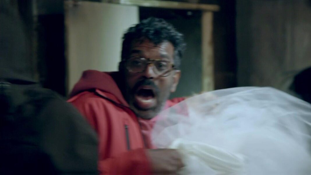 Romesh Ranganathan lets out a scream while holding a dead woman's wedding dress in the haunted cabin