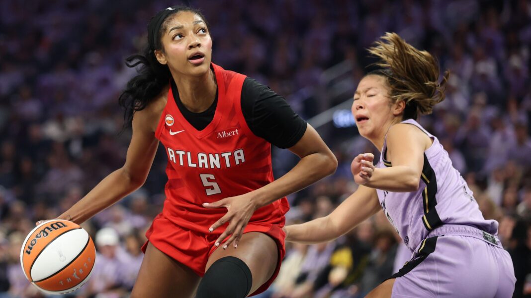 Angel Reese in a red Atlanta Dream kit, dribbles past Kaitlyn Chen in a mauve Golden State Valkyries kit
