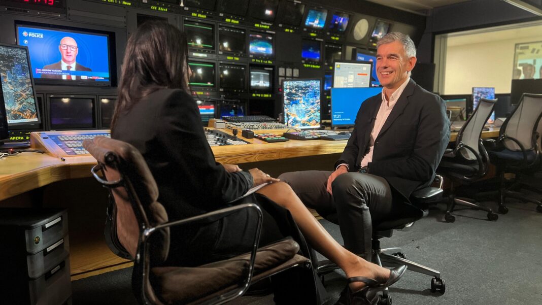 BBC director general defends plan to shelve new Archers studio A woman and a man sit facing each other in a television control room interview setting, surrounded by monitors, control panels and broadcasting equipment.