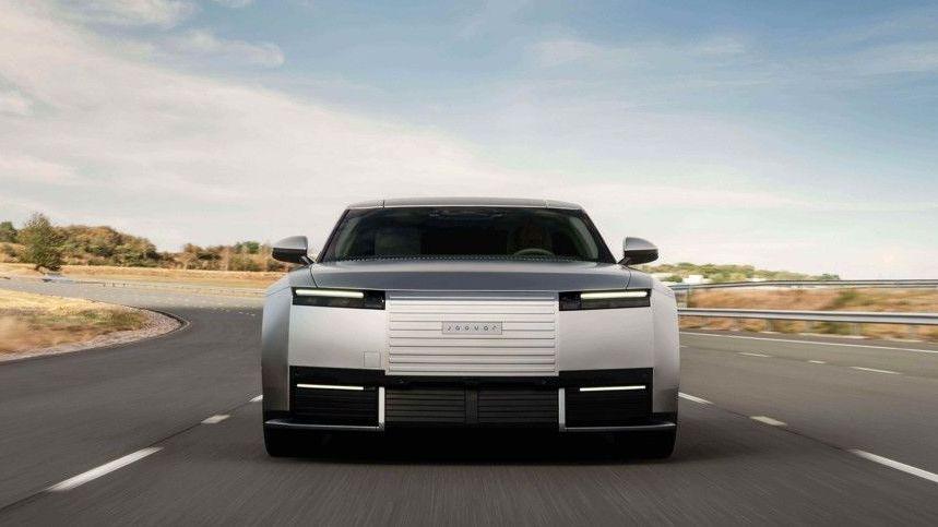 A grey Jaguar car drives fast on a highway.