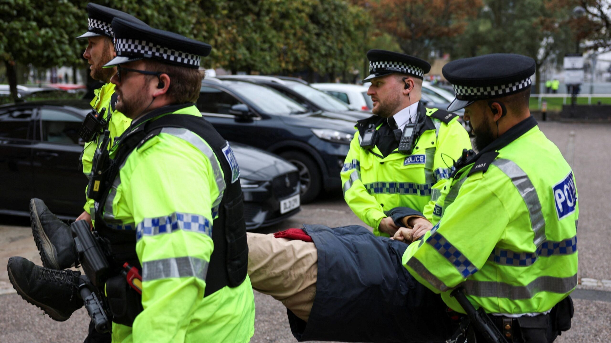 Police officers wearing yellow hi-vis jackets remove an anonymous Palestine Action supporter amid a protest outside the Labour Party’s annual conference in Liverpool.