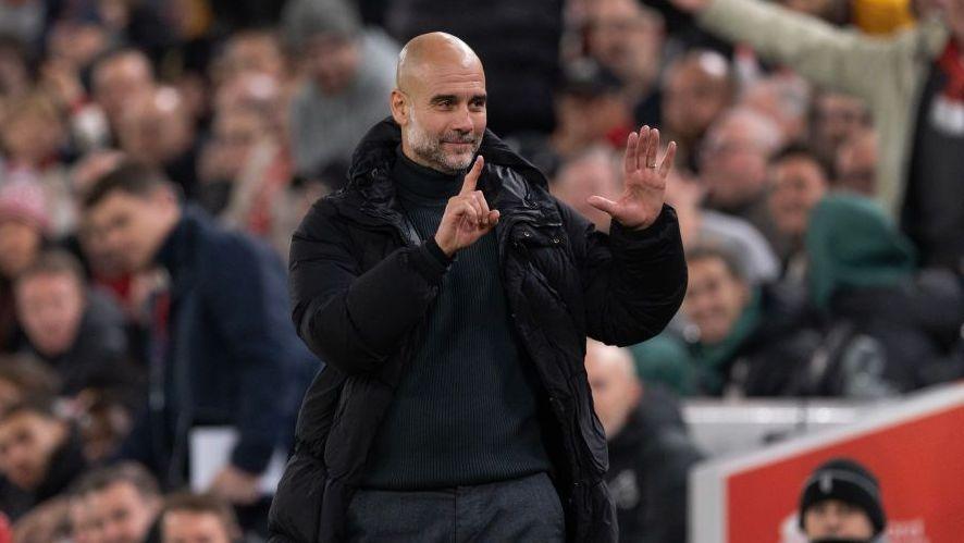 Manchester City manager Pep Guardiola holds up six fingers to indicate the six premier league titles he has won after Liverpool fans sing 'You're Getting Sacked it in Morning'