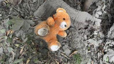 An orange teddy bear lies in the ash and rubble near the site of a Russian glide bomb attack